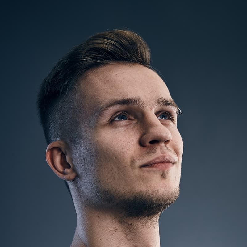 Kuba Florczuk looking up, calm, on a blue-grey studio backdrop